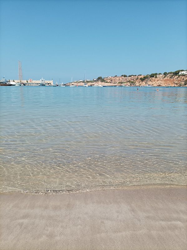 A serene beach scene with clear water and a distant coastline.