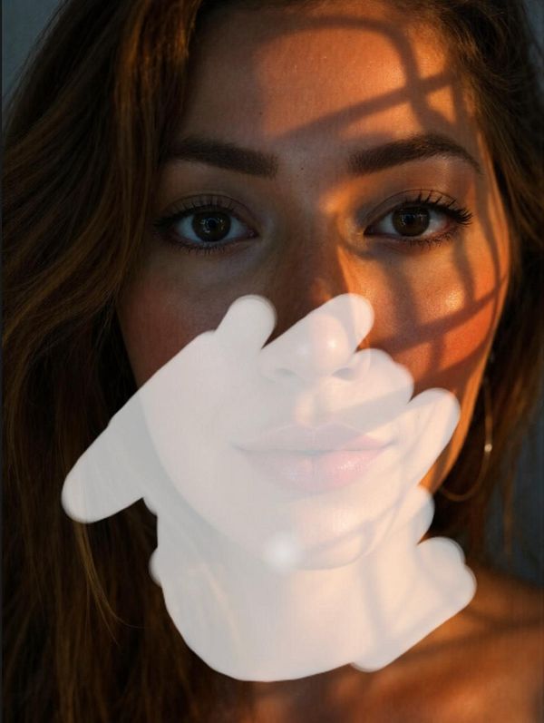 A close-up portrait of a woman with a hand-shaped inpainting effect over her face.