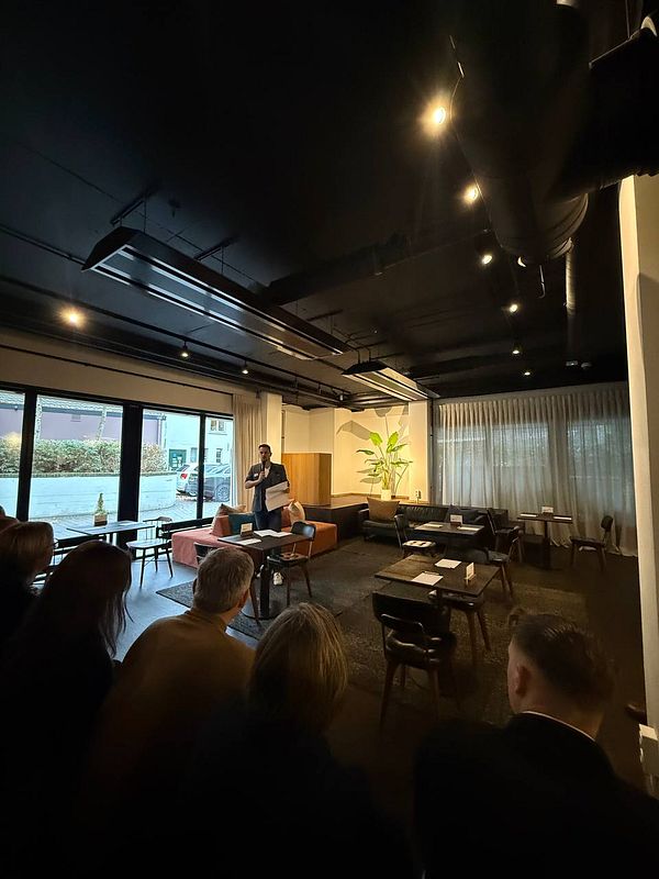 A speaker addresses a small audience in a modern, stylish venue in Eindhoven.