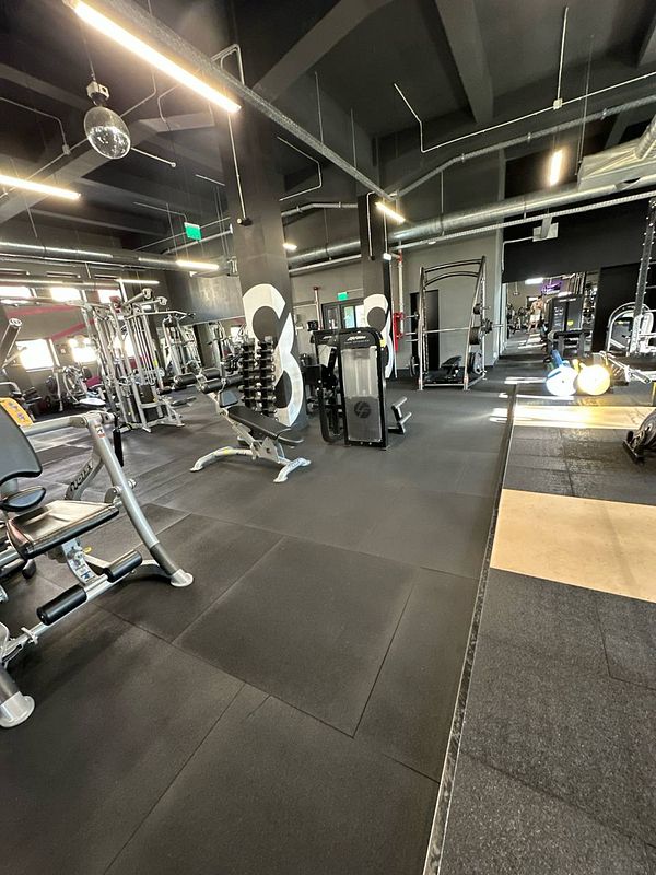 A spacious gym interior featuring various workout equipment and a modern design.