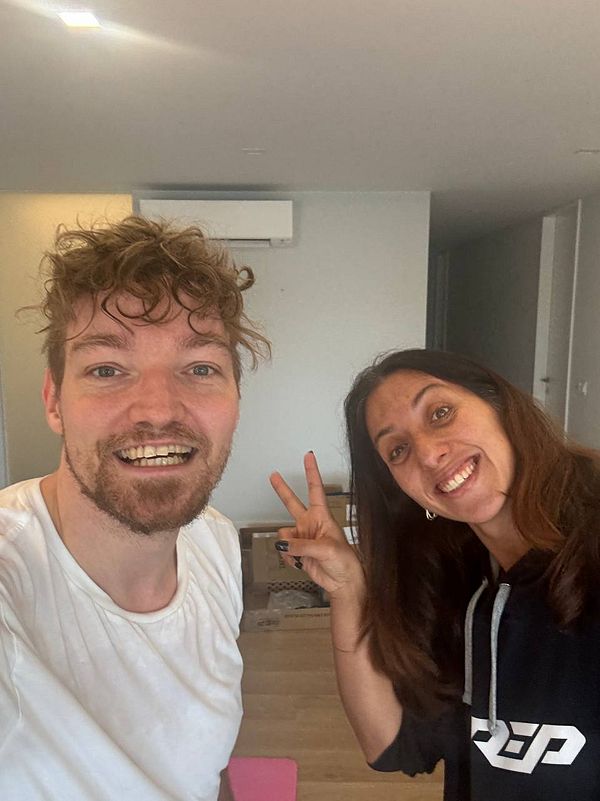 Two smiling individuals pose together in a gym setting.