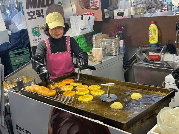 A vendor is frying food at a market stall.