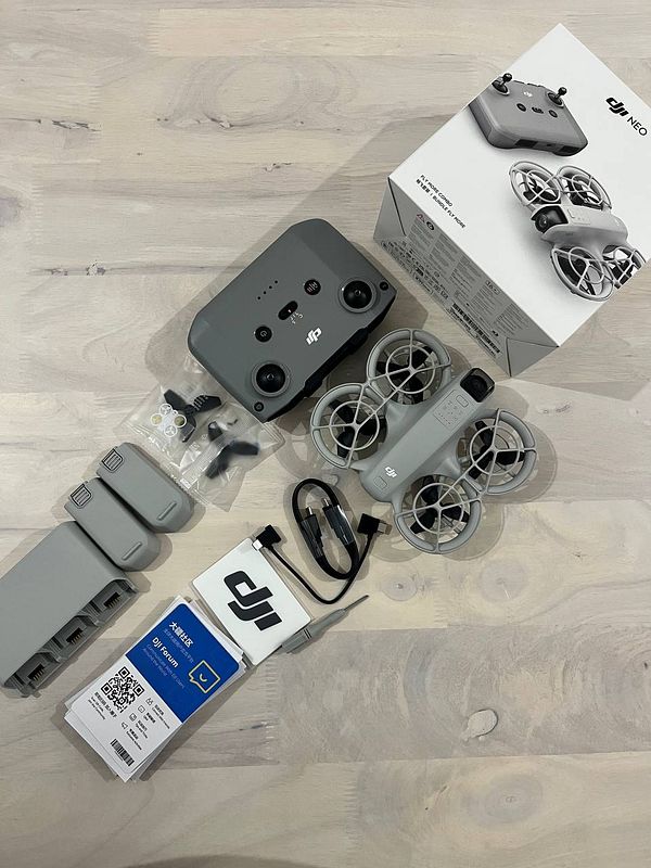 The image displays a DJI drone kit with various accessories laid out on a light wooden surface.