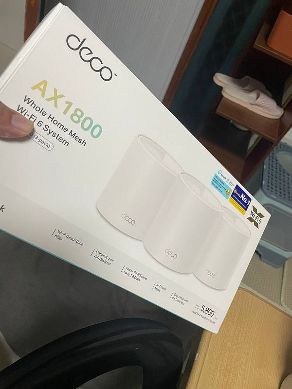 Photo of a TP-Link Deco mesh wifi system setup with three units displayed on a wooden surface in a home setting.