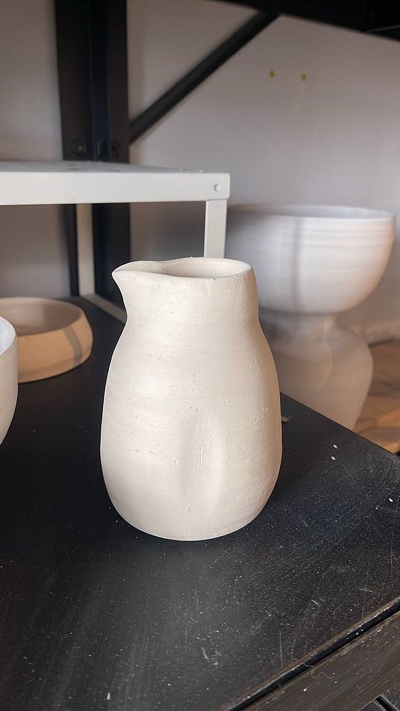 Close-up of a pair of pottery mugs on a wooden surface, styled with white and teal glaze.