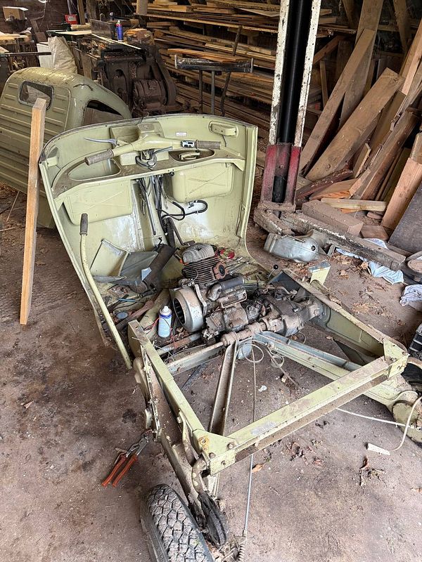 A photo of an engine block separated from a vehicle inside a garage or workshop.