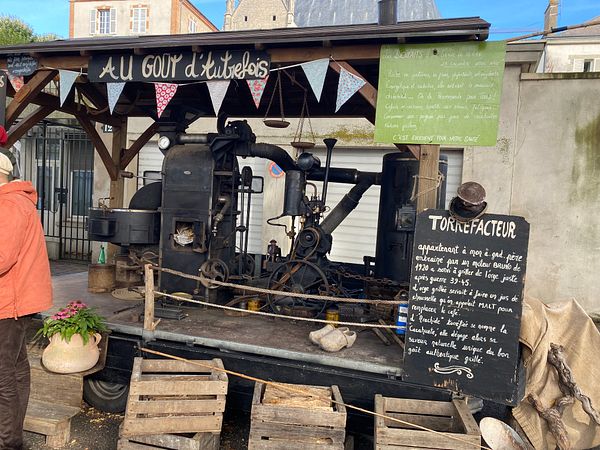 A vintage coffee roasting setup is displayed at a market stall.