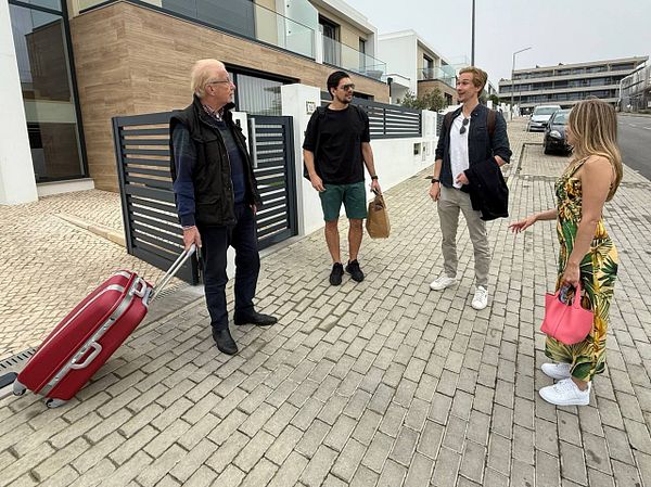 A group of four people is gathered outside a modern building, engaging in conversation.