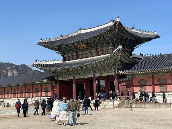 Gyeongbokgung Palace features traditional Korean architecture with visitors exploring its grounds.