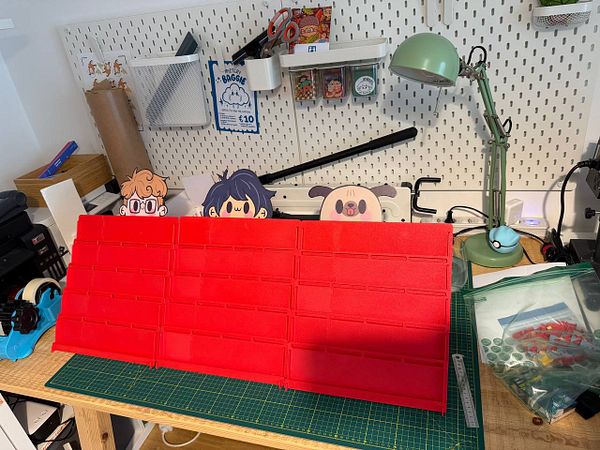 A workspace featuring a red foam board display with cartoon character cutouts and various crafting supplies.