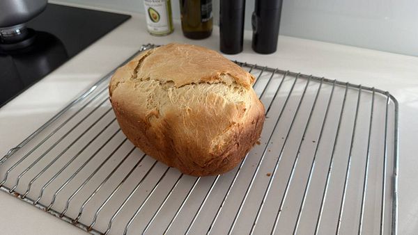 A freshly baked loaf of brioche bread cooling on a wire rack in a kitchen.