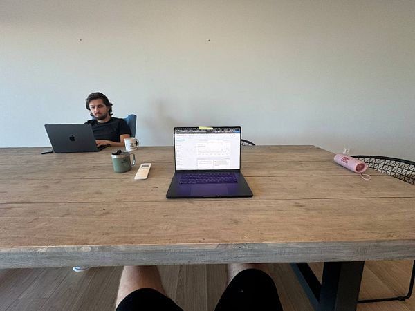 A coworking space featuring two individuals working at a large wooden table.