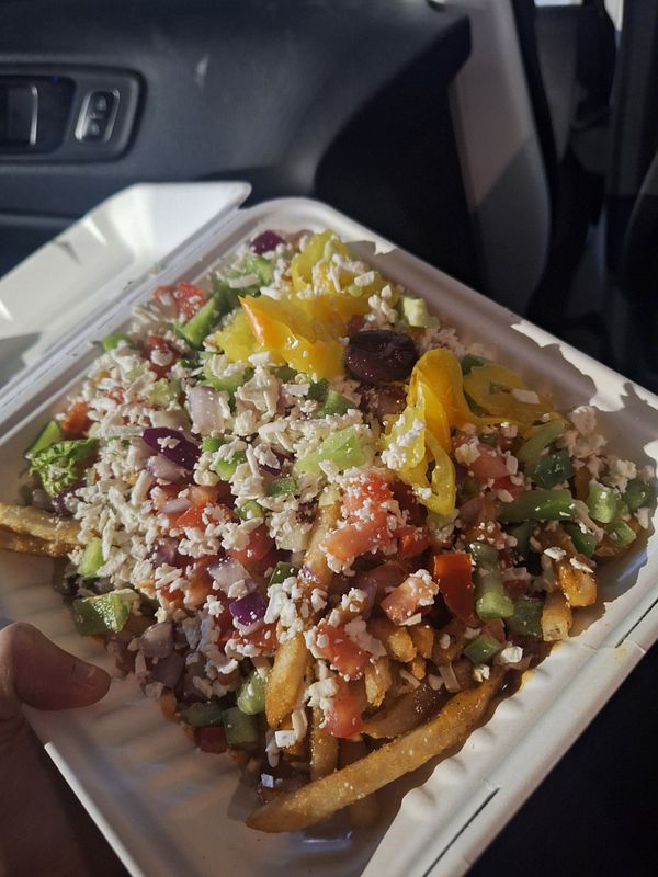 A colorful plate of loaded fries topped with various fresh ingredients.