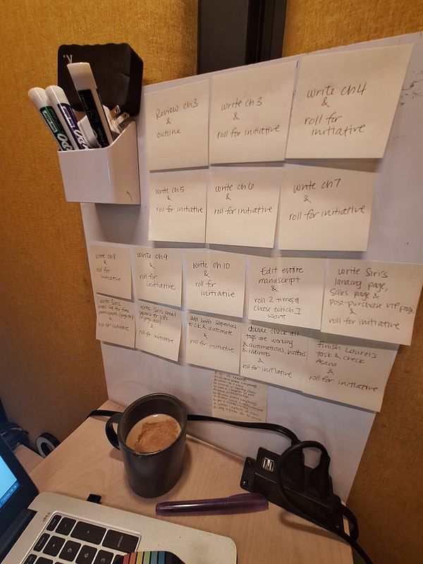 A workspace featuring a wall of sticky notes with tasks and a coffee mug on a desk.