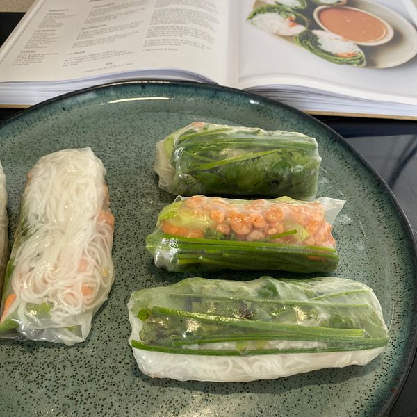 A plate of freshly made spring rolls alongside an open cookbook.