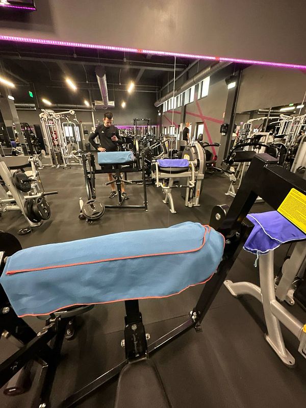 A gym interior featuring various exercise machines and a person checking their phone.