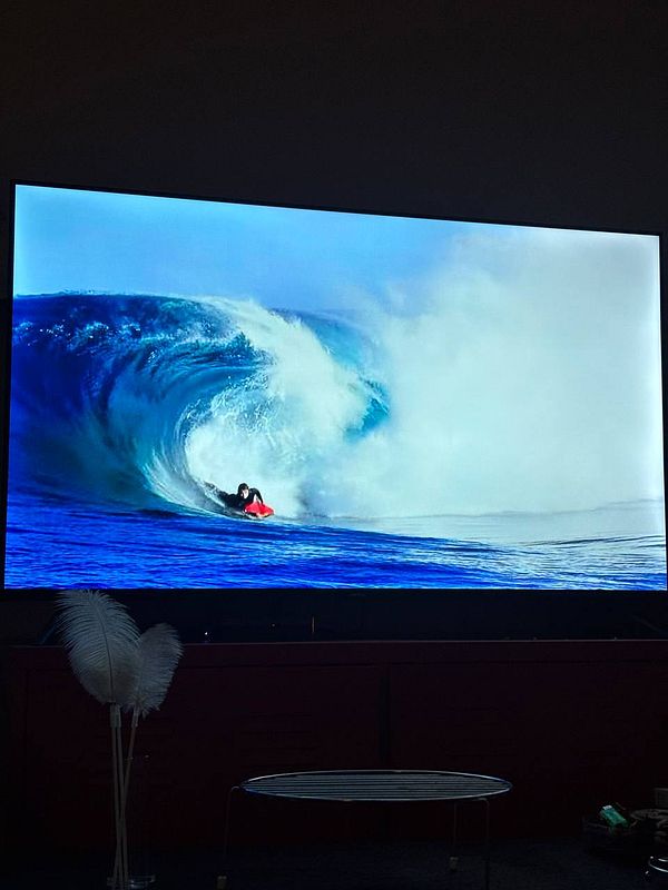 A surfer rides a large wave on a television screen.