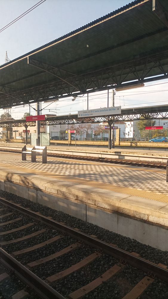 A view of a train station platform with tracks and signage.