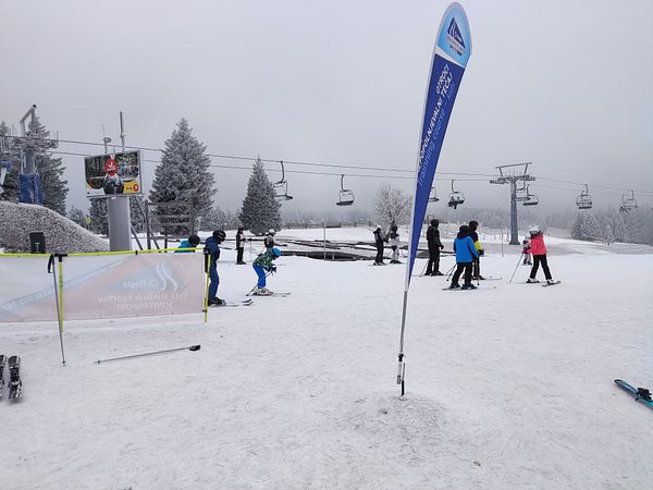 A snowy ski resort scene with skiers preparing to hit the slopes.