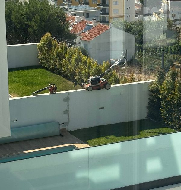 Gardeners are using equipment to maintain a lawn in a residential area.