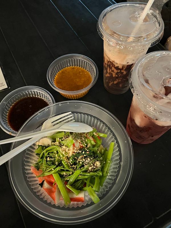 A colorful steamboat meal featuring a fresh salad and drinks.