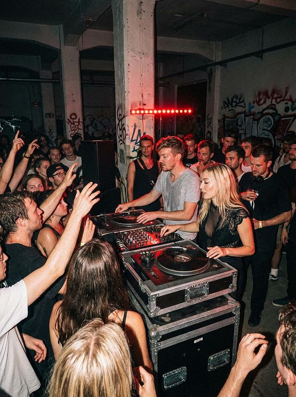A lively crowd enjoys a DJ performance in an urban setting.
