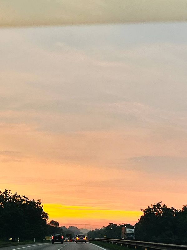 A scenic view of a sunset while driving on a highway.