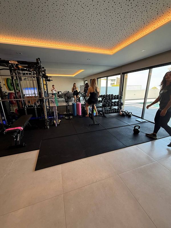 A modern gym space featuring workout equipment and individuals engaged in fitness activities.