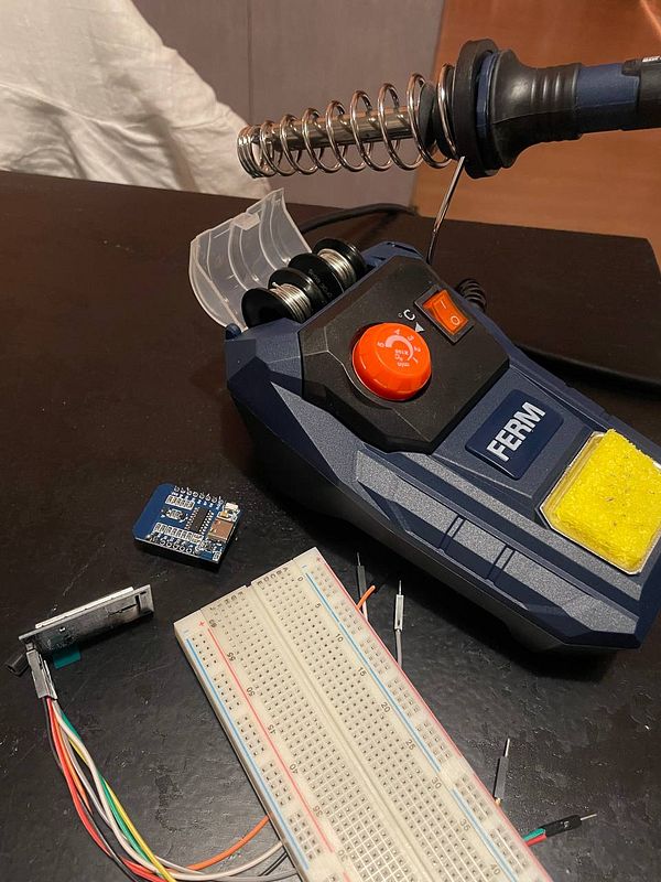 An electronic project setup on a wooden table featuring a circuit board with various components connected by multicolored wires.