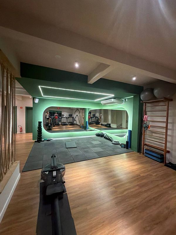 Photograph of a white side table with a plant, a small decorative item, and a book against a pink wall.