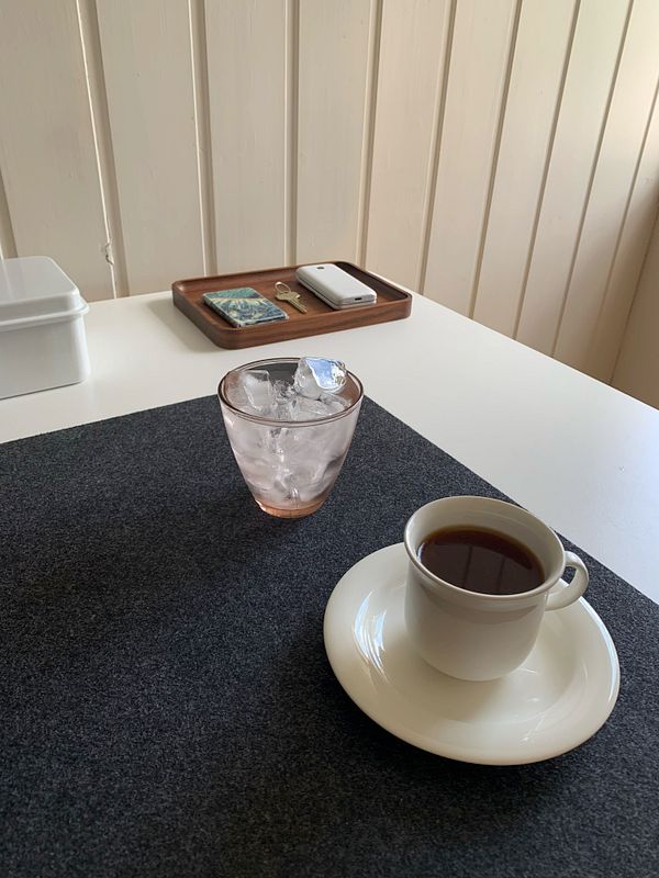 A cozy coffee setup featuring a cup of freshly brewed coffee and a glass of ice.