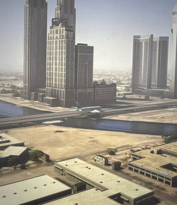 A view of a modern cityscape in Dubai featuring tall skyscrapers and an airplane flying low over a waterway.