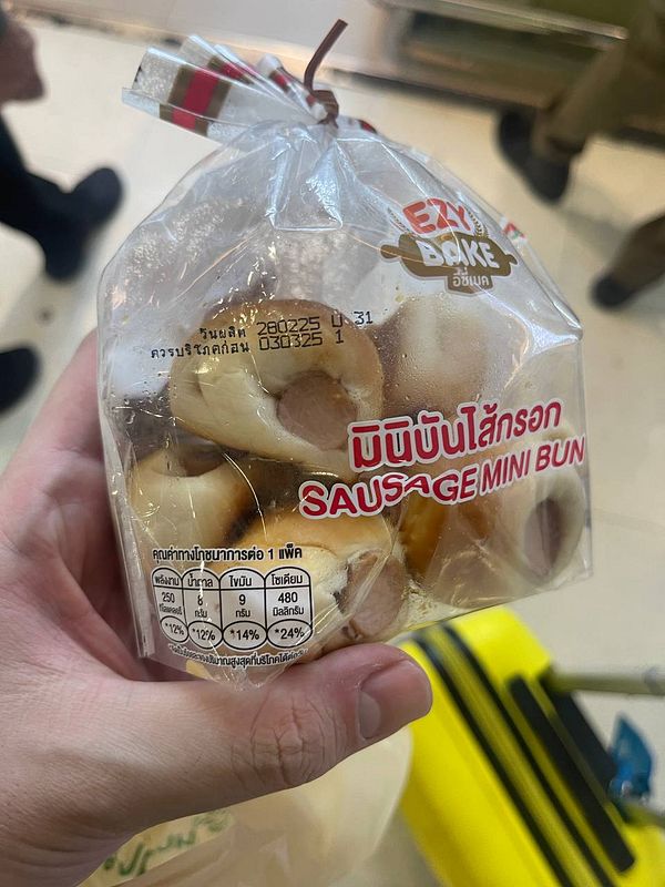 A hand holds a transparent bag containing mini sausage buns.