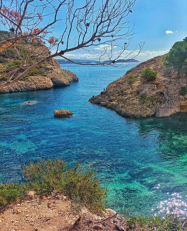 A scenic coastal view featuring clear turquoise waters and rocky cliffs.