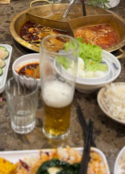 A table set for a hotpot meal featuring various dishes and drinks.