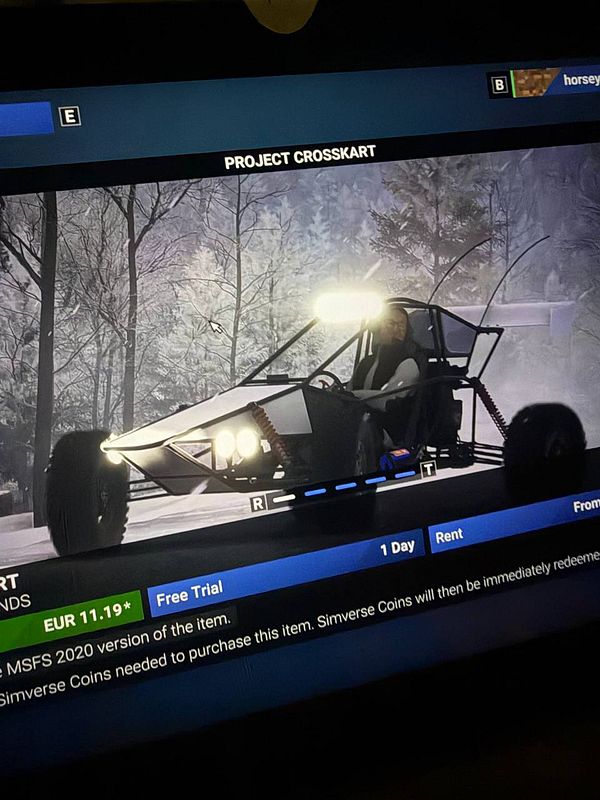 Photo of a red buggy car parked near a modern building with greenery in the foreground.