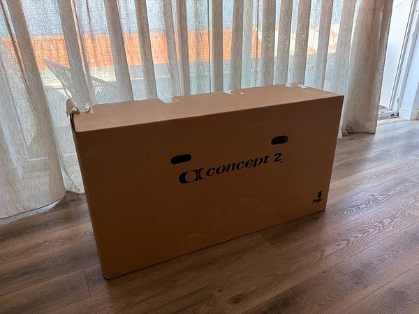 A modern exercise bike positioned in a well-lit living room near a window.