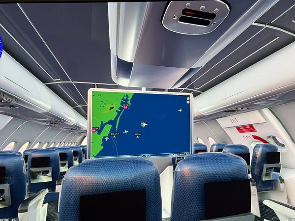The image depicts the interior of an airplane cabin with a flight map displayed on a screen.