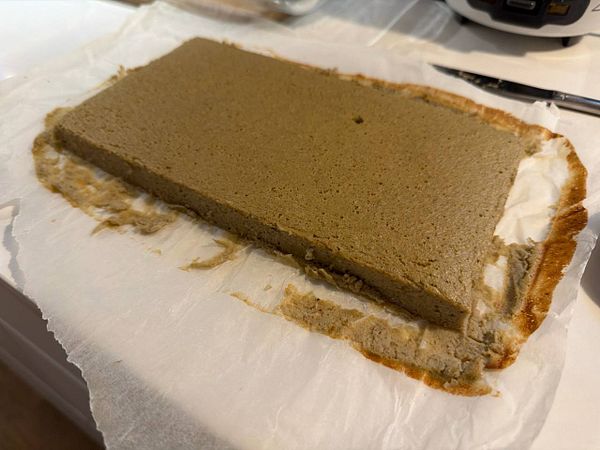 Stack of thick rectangular banana pancakes with melting butter on a white plate.