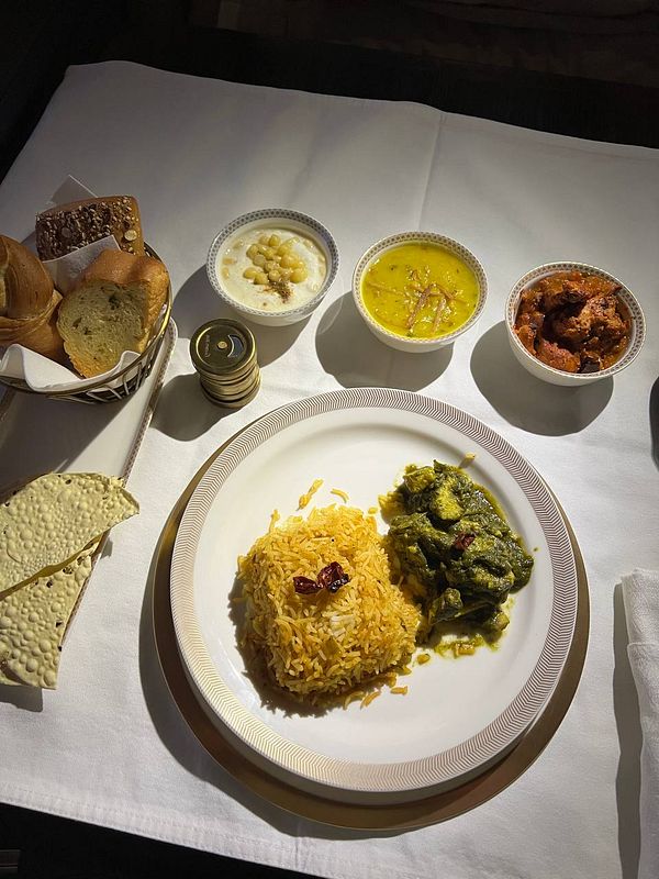 An elegant in-flight meal featuring a variety of Indian dishes served on a white tablecloth.