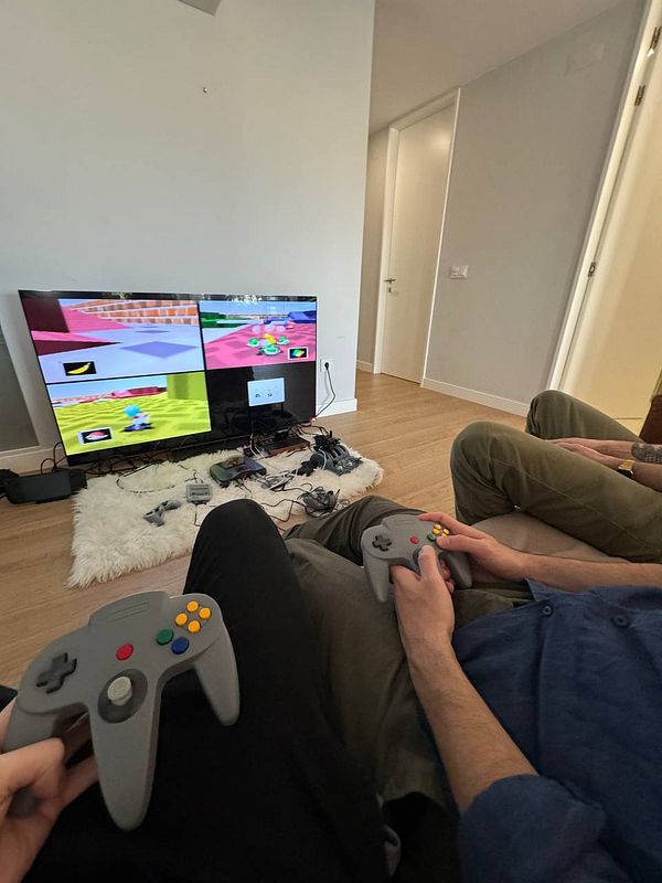 A group of friends is enjoying a gaming session with multiple screens and controllers.