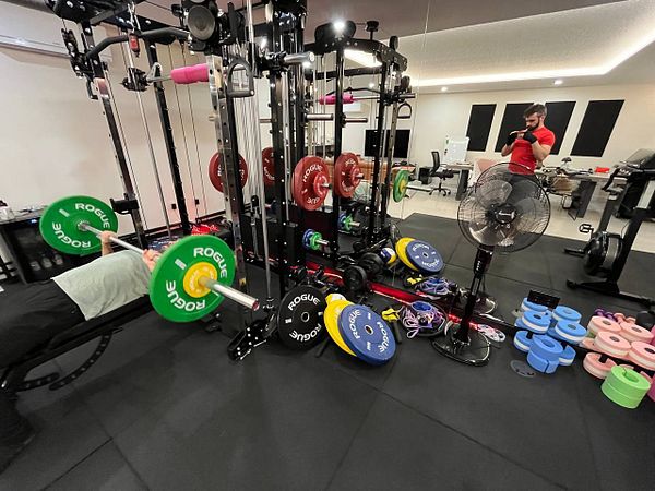 A well-equipped home gym featuring various weightlifting equipment and a person exercising.