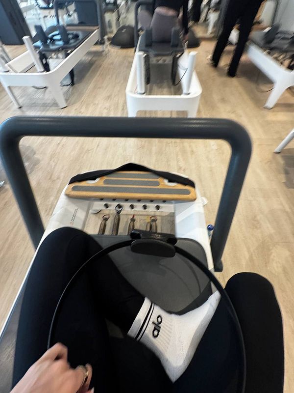 The image captures a view from a Pilates reformer machine in a gym setting.