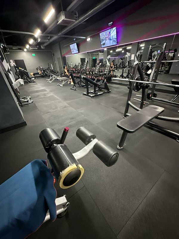 A well-equipped gym interior featuring various workout machines and weights.