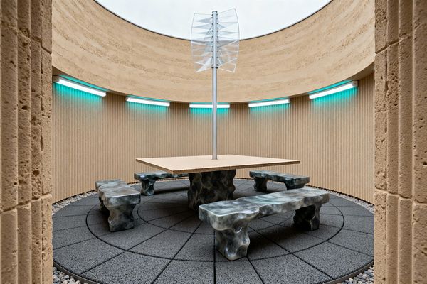 A circular open-air patio with sand-beige ribbed walls and an oculus above. Teal LED light bars line the perimeter. In the center, a square layered-wood tabletop hovers on a dark, sculptural base with a slim aluminum mast topped by translucent fins. Four matching smoky-gray marbled benches sit on dark radial pavers, with a ring of gravel at the edge.