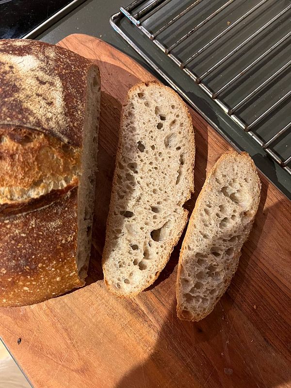 A freshly baked sourdough loaf with two slices cut from it.
