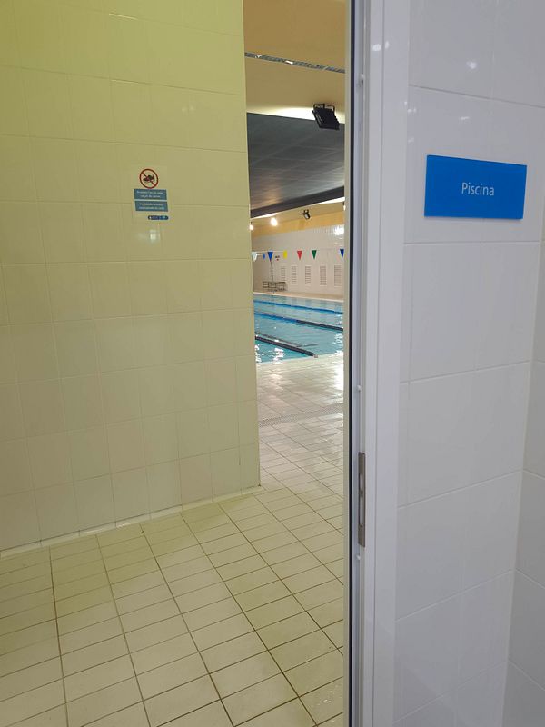 Image of a lake with mountains reflected in the calm water under a cloudy sky.
