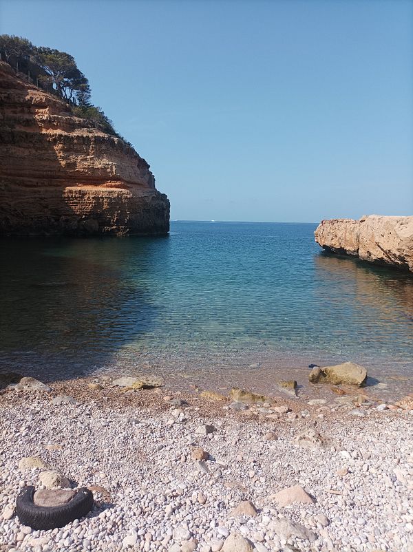 A serene coastal scene featuring clear water and rocky cliffs.