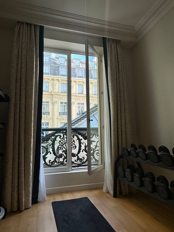A gym space with a view of Parisian architecture through a large window.
