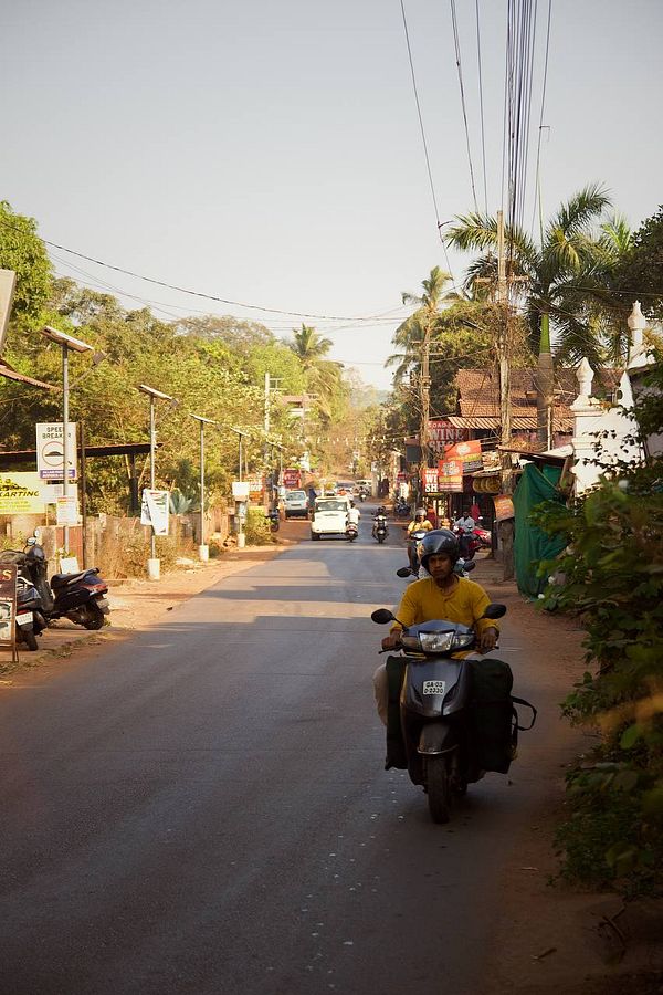 A busy street scene in Goa with a motorcyclist and various vehicles.